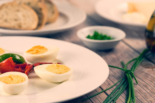 Delicious homemade sliced boiled eggs served with herbs and vegetables on a rustic wooden table.