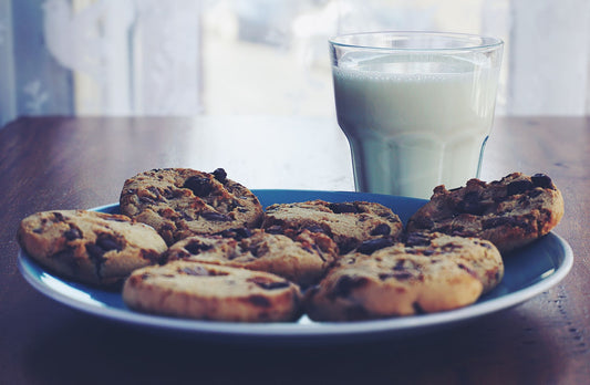 Chocolate chip cookies on a plate with a glass of milk, perfect breakfast treat.