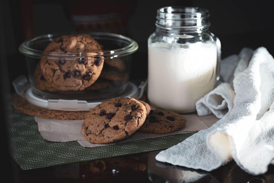 A cozy afternoon snack setup featuring chocolate chip cookies and a glass of milk.