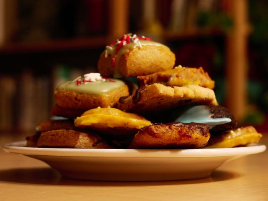 A close-up shot of colorful assorted cookies stacked on a white plate.