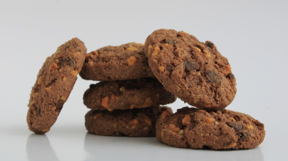 Close-up of six chocolate cookies stacked on white surface, perfect for any snack.