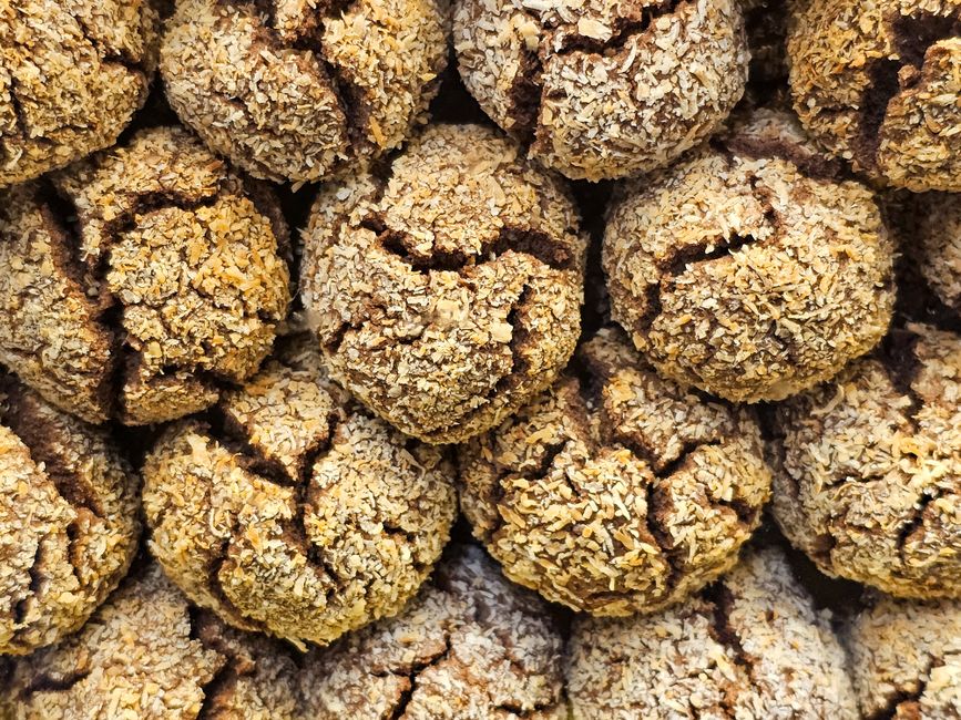 A detailed close-up of stacked crunchy coconut cookies showing texture and cracks.