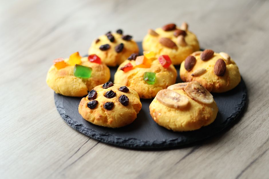 Delicious homemade cookies topped with nuts, raisins, and candied fruits on a slate plate.