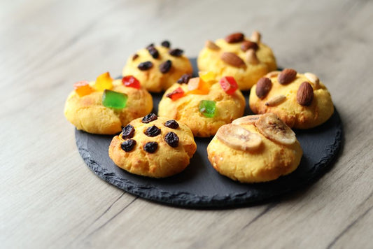 Delicious homemade cookies topped with nuts, raisins, and candied fruits on a slate plate.