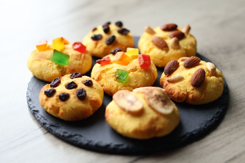 Delicious homemade cookies topped with nuts, raisins, and candied fruits on a slate platter.