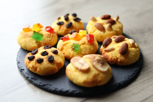 Delicious homemade cookies topped with nuts, raisins, and candied fruits on a slate platter.