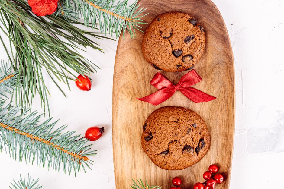 Top view of chocolate chip cookies with Christmas decorations and a red bow.