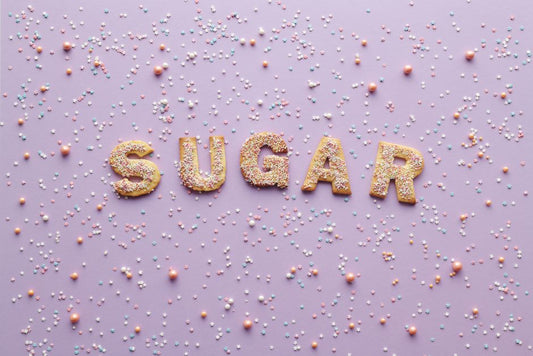 Colorful sprinkle-covered cookies spelling 'sugar' on a pastel purple background, creating a sweet and playful flatlay design.