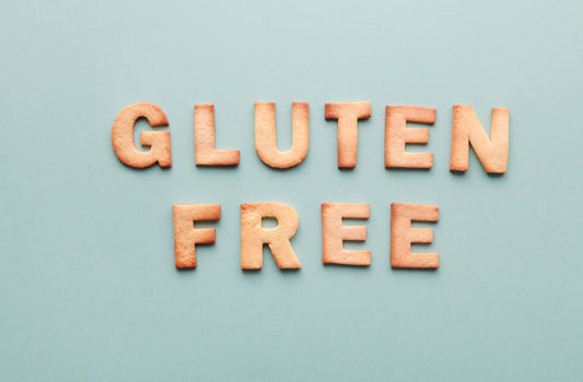 Gluten-free cookie letters form a phrase on a turquoise background, ideal for allergy awareness.