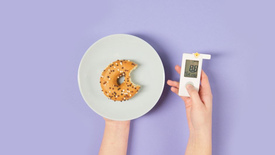 A bitten donut on a plate and a glucometer symbolizing sugar levels and diabetes awareness.