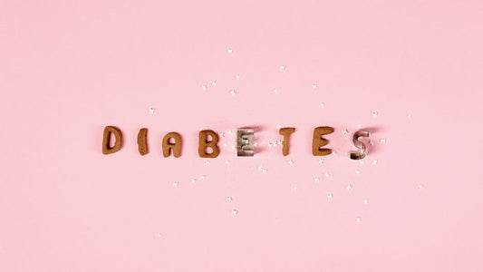 Pink background with the word 'Diabetes' formed from cookie cutters and sugar pieces.