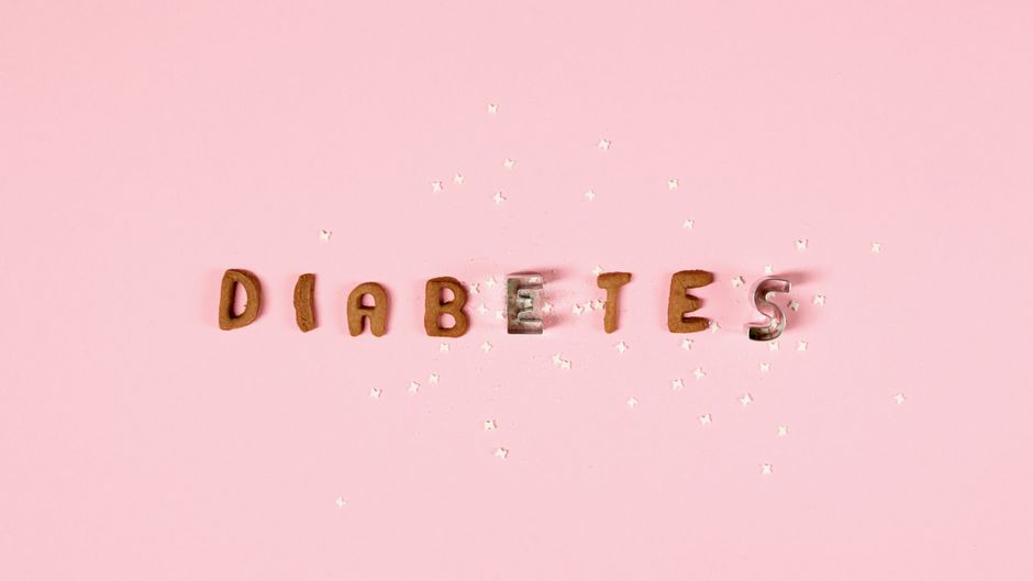 Pink background with the word 'Diabetes' formed from cookie cutters and sugar pieces.
