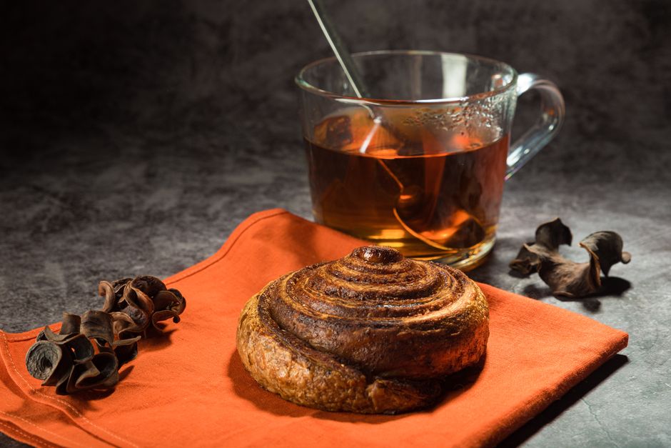 Close-up of a cinnamon roll and tea on a table, perfect for breakfast or a cozy brunch setting.