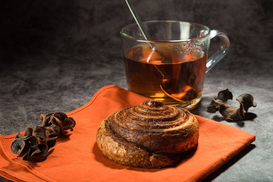 Close-up of a cinnamon roll and tea on a table, perfect for breakfast or a cozy brunch setting.