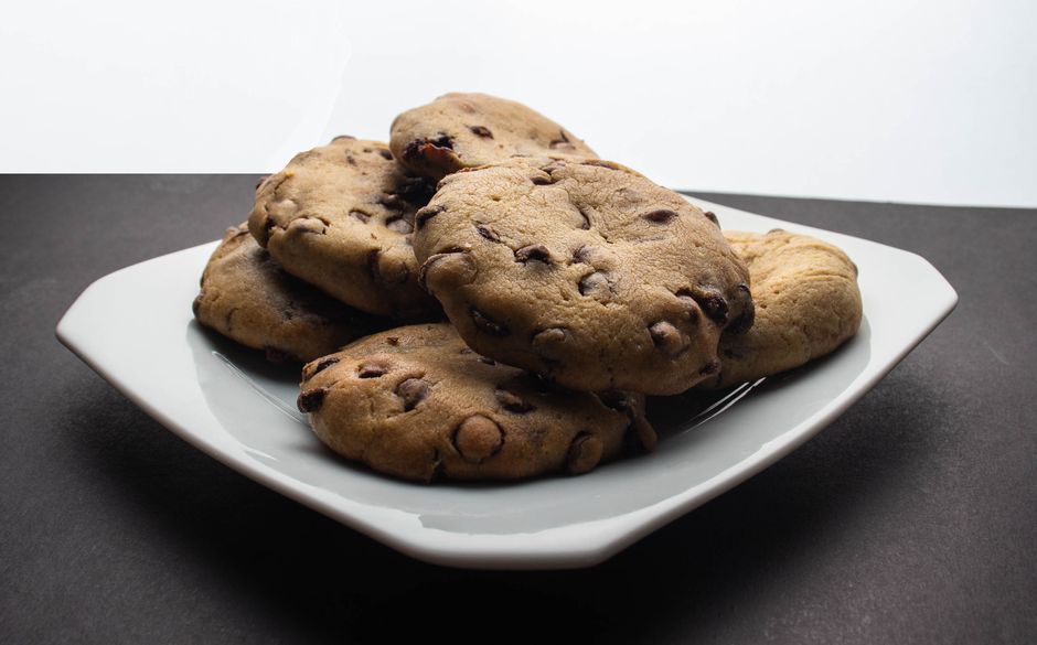 Sumptuous chocolate chip cookies stacked on a white plate, ready to enjoy.