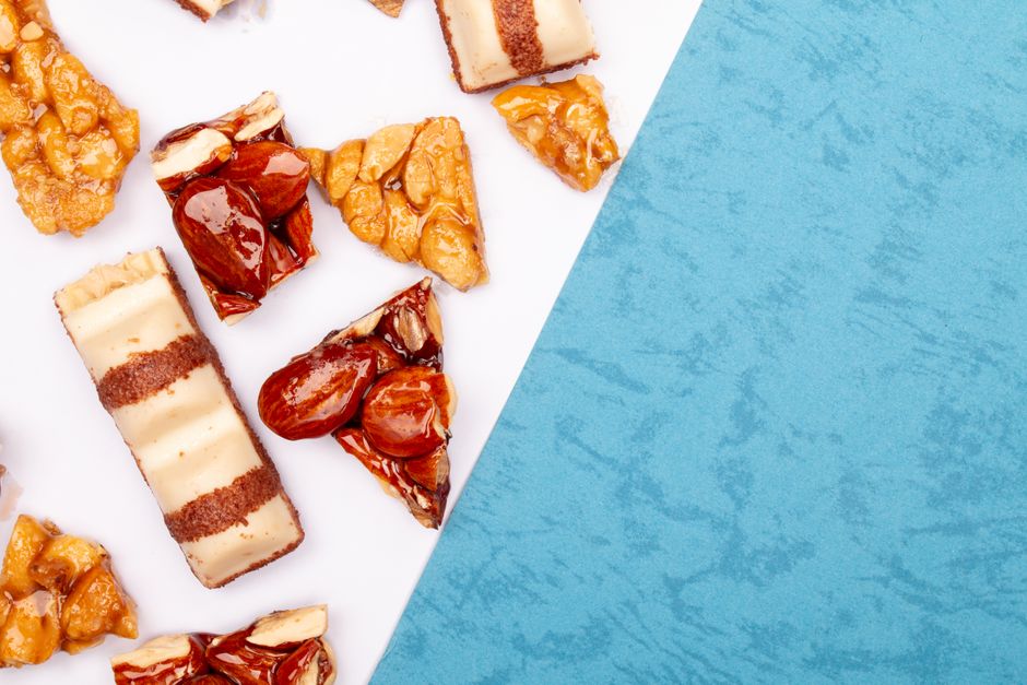 Flat lay of assorted candied nuts and pastries on a blue and white surface, offering copy space.