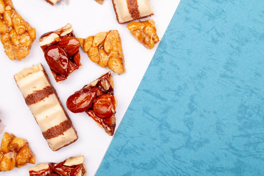 Flat lay of assorted candied nuts and pastries on a blue and white surface, offering copy space.