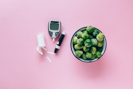 Top view of a glucometer and fresh Brussels sprouts on a pink background promoting health.