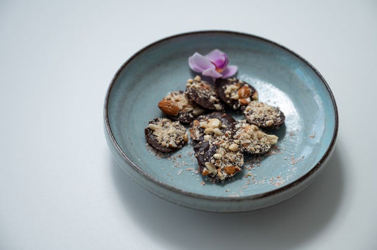 Delicious chocolate bark sprinkled with nuts, served in a ceramic bowl with an orchid garnish.