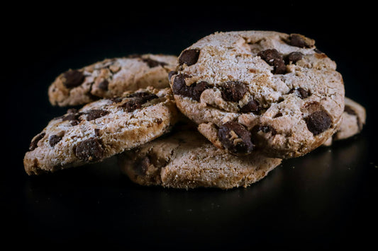 Tasty chocolate chip cookies arranged on a dark surface, perfect for food photography.