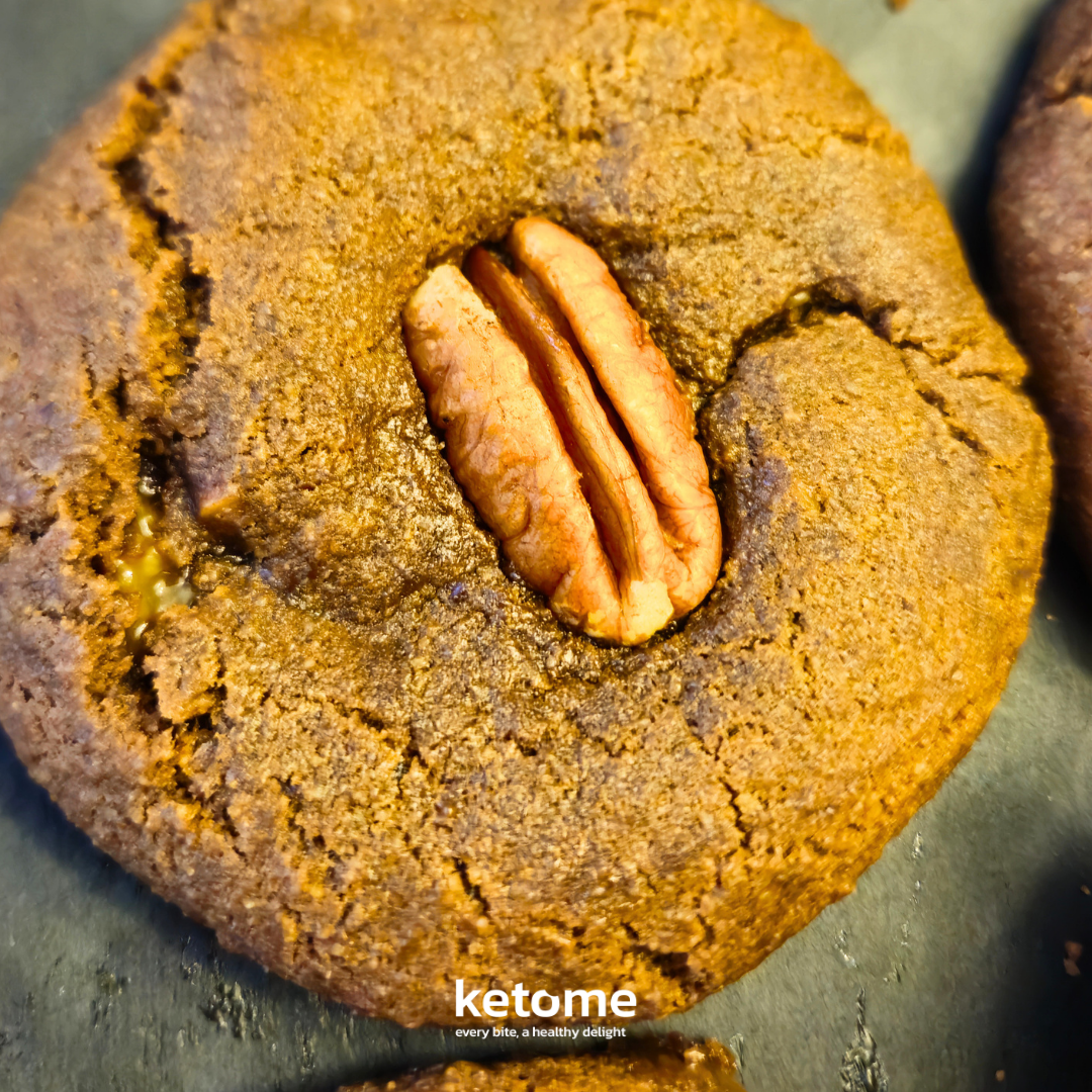Close-up of a pecan cookie with 'ketome' branding on a dark surface